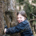 Une jeune fille souriante étreint un arbre dans un cadre forestier serein, profitant de la nature.